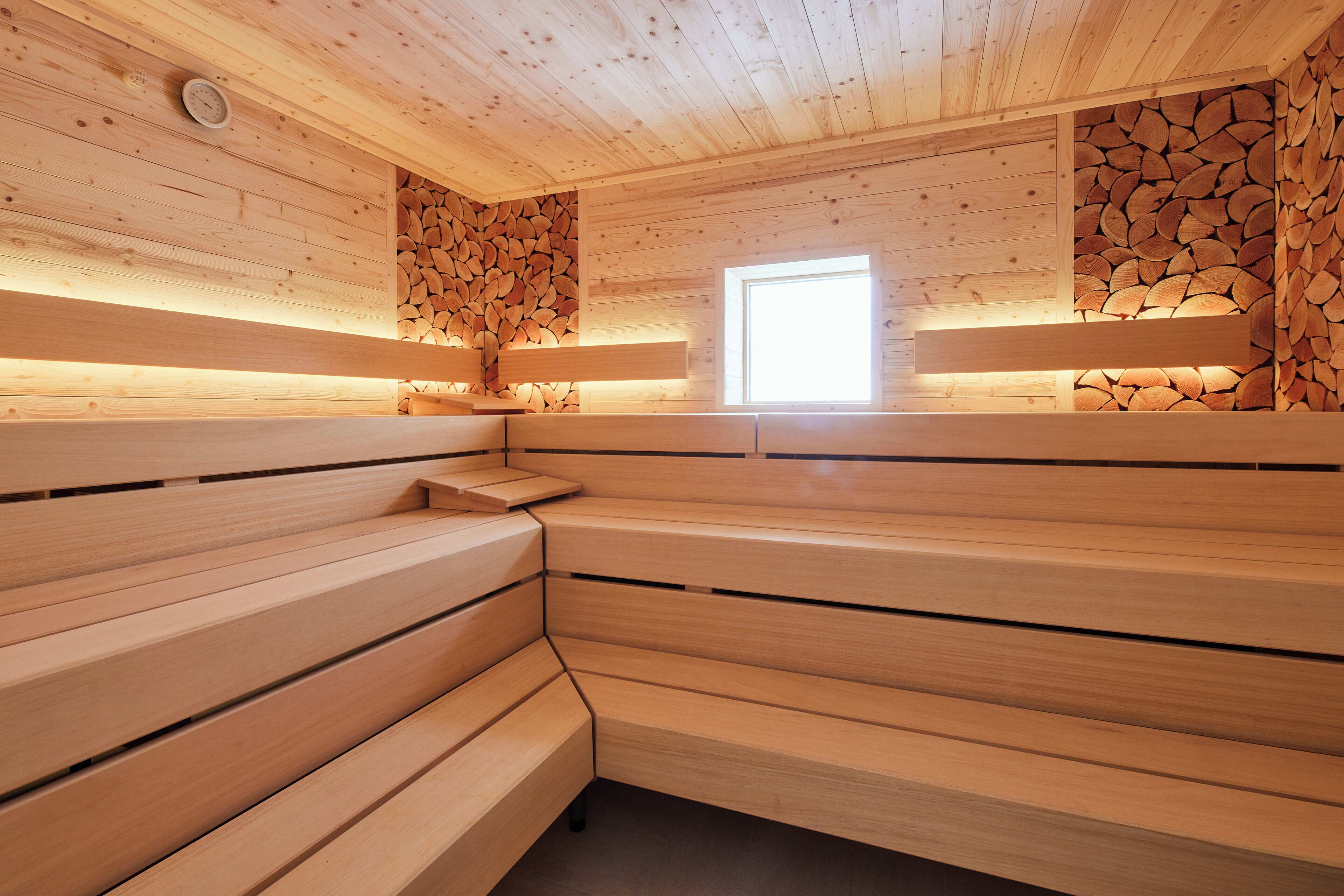 Una sauna con bancos de madera y una pared de troncos.