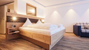 Camera moderna con un letto in legno, comodini integrati, uno specchio e un divano a quadri.