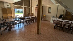 A spacious dining area with a long table and chairs, a high ceiling, and a view of the outdoors. - Large house near Paris, garden, for 12 people (Yèvre-la-Ville-Yèvre le Châtel)