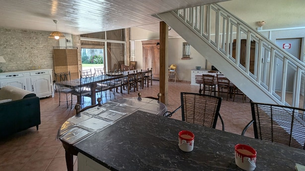 A spacious kitchen with a long dining table, a staircase, and a view of the outdoors. - Large house near Paris, garden, for 12 people (Yèvre-la-Ville-Yèvre le Châtel)