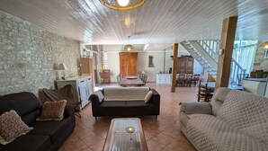 A spacious living area with a high ceiling, stone walls, and a dining area with a long table and chairs. - Large house near Paris, garden, for 12 people (Yèvre-la-Ville-Yèvre le Châtel)
