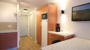 A compact kitchen with a microwave, refrigerator, and coffee maker. - Beautiful T2 apartment with balcony and parking in Mont-Dore (Mont-Dore)