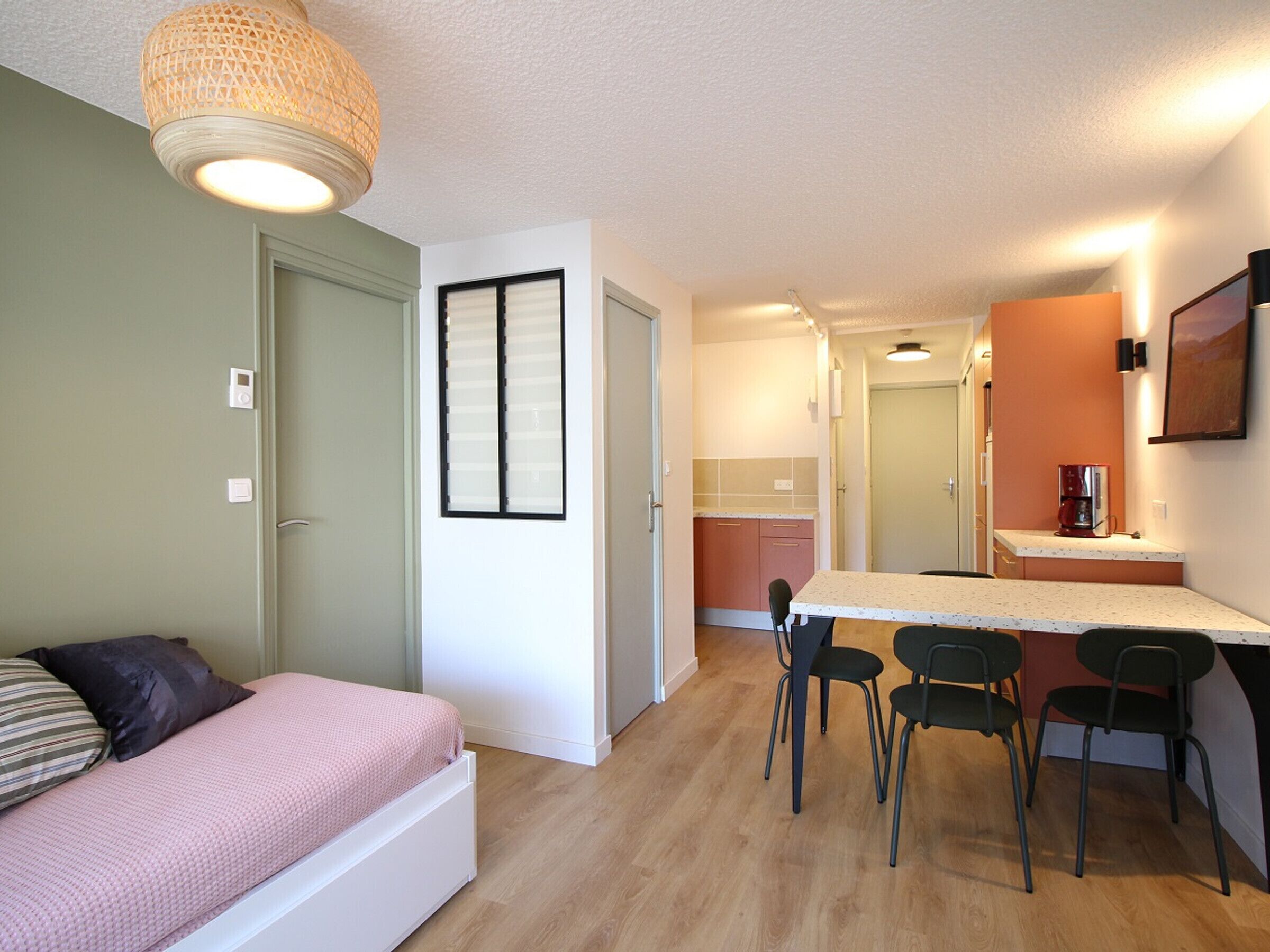 Une pièce de taille modeste comprenant un lit, un coin cuisine et un espace repas.