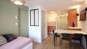 A compact room with a bed, a kitchenette, and a dining area. - Beautiful T2 apartment with balcony and parking in Mont-Dore (Mont-Dore)