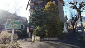 A multi-story residential building with a prominent balcony on the second floor. - Beautiful T2 apartment with balcony and parking in Mont-Dore (Mont-Dore)