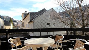 A balcony with a round table and four wooden chairs. - Beautiful T2 apartment with balcony and parking in Mont-Dore (Mont-Dore)