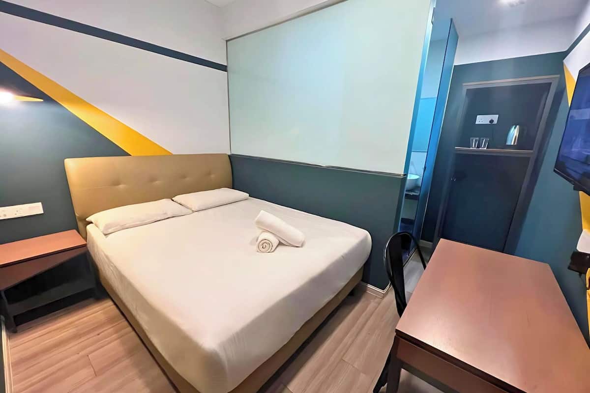Quarto de hotel com uma cama, escrivaninha e televisão.