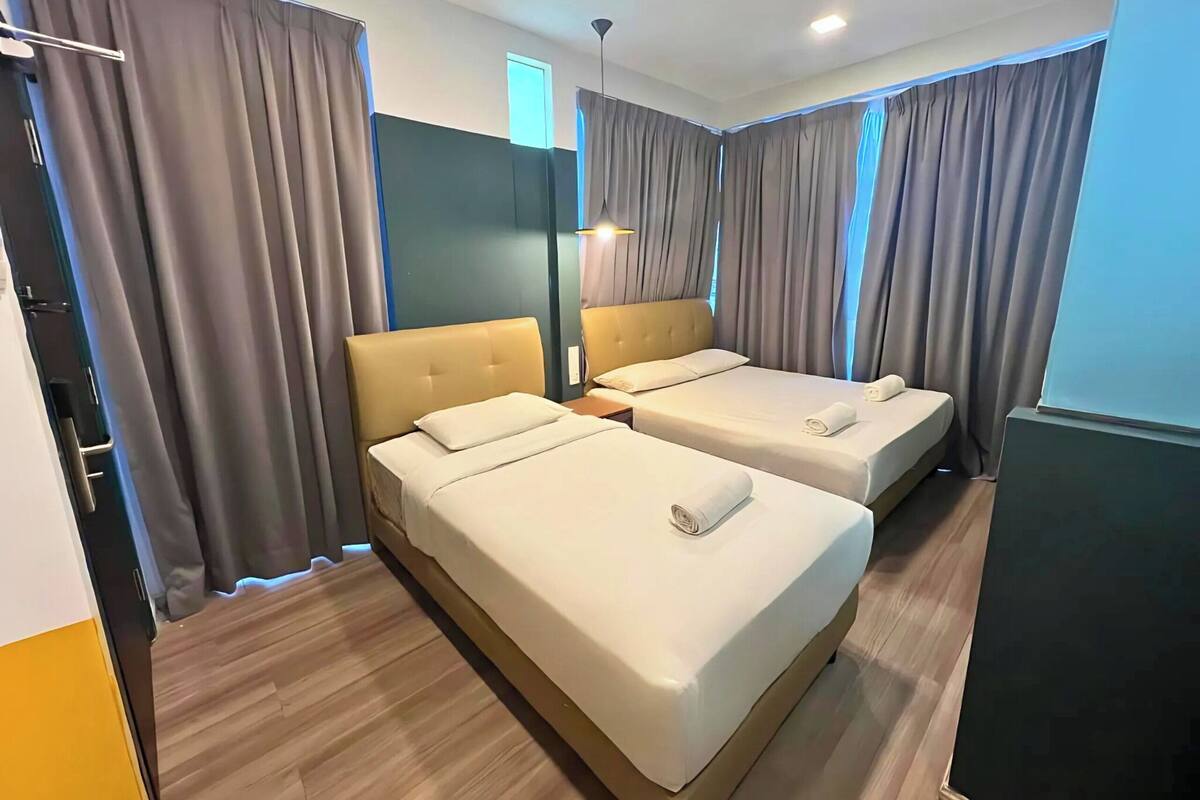 Quarto de hotel com duas camas, um guarda-roupa e um espelho.
