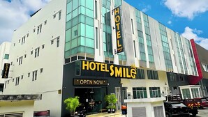 A modern hotel with a prominent 'Hotel Smile' sign, large windows, and a clear sky. - Smile Hotel Subang Airport (Shah Alam)