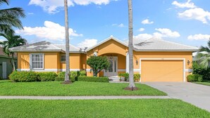 A residential house with a garage, a well-maintained lawn, and palm trees. - The Sandbar - 3BDR Courtyard Home w/Pool & Spa (Marco Island)