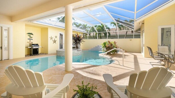 An indoor swimming pool with lounge chairs, a grill, and a covered patio area. - The Sandbar - 3BDR Courtyard Home w/Pool & Spa (Marco Island)