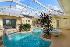 A swimming pool with a glass ceiling, surrounded by plants and a hot tub.
