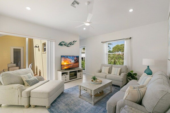 A living room with a television, sofas, a coffee table, and a ceiling fan.