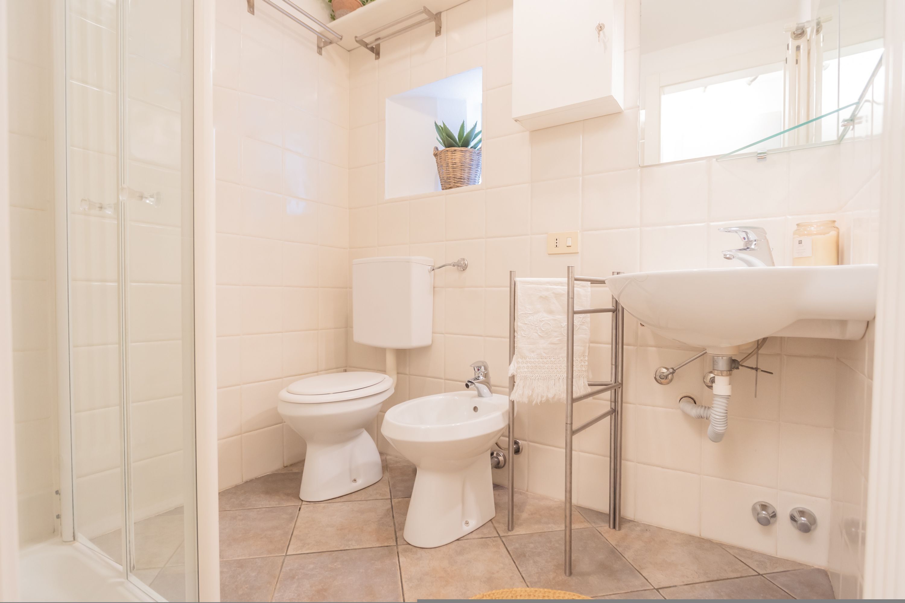 A bathroom with a shower, toilet, bidet, and sink.