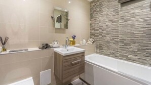 Un baño moderno con un espejo grande, una bañera y un tocador con lavamanos.