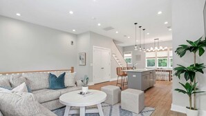Un salon moderne avec un canapé, une table basse et un coin cuisine à l’arrière-plan.