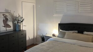 Una camera da letto con un letto, una ventola a soffitto, una cassettiera e un comodino con una lampada.