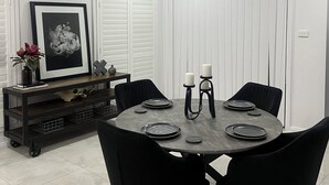 Zona pranzo con un tavolo rotondo, sedie nere e pareti bianche.