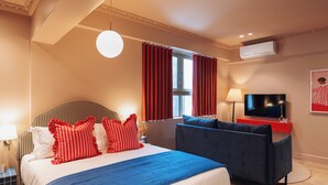 Een hotelkamer met een bed, een bank, een televisie en een raam met gordijnen.