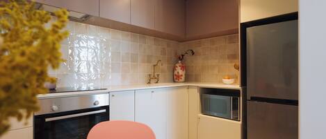 A modern kitchen with white cabinets, a stainless steel refrigerator, a microwave, and a stove.