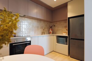 A modern kitchen with white cabinets, a stainless steel refrigerator, a microwave, and a stove.