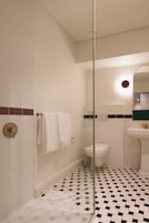 A bathroom with a glass shower enclosure, a toilet, and a sink with a mirror.