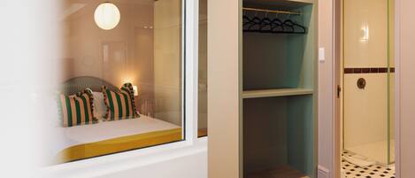 Une chambre d’hôtel comprenant un lit, un coin fenêtre, un placard et un espace douche.