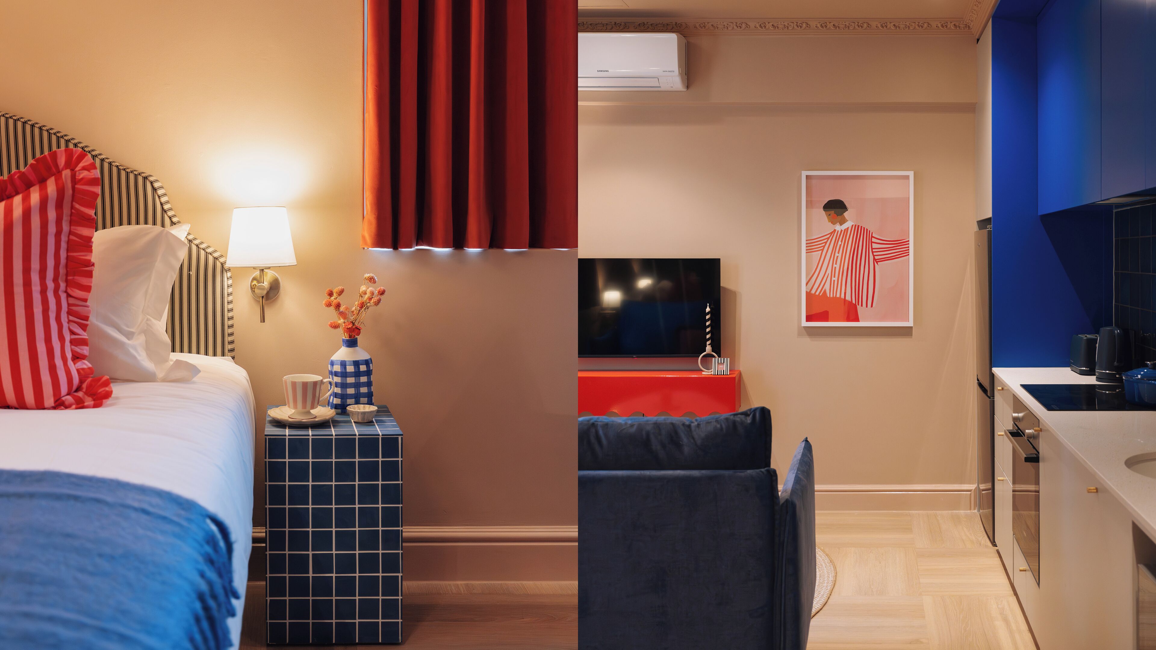A hotel room with a bed, bedside table, lamp, and a small table with a vase and cup.