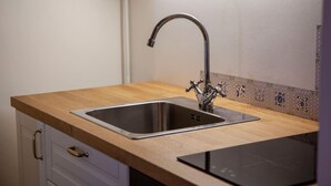 A kitchen with a stainless steel sink, wooden countertop, and a patterned backsplash. - Navigli Beautiful Apartment in MILAN Near TRAM (Milano)
