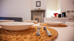 A dining area with white plates and cutlery on woven placemats, a sofa, and a fireplace in the background. - Navigli Beautiful Apartment in MILAN Near TRAM (Milano)