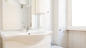 A bathroom with a white sink, mirror, and toilet.