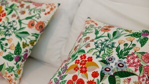 A bed with two pillows, one with a floral pattern and the other plain white.