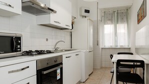 A compact kitchen with white cabinets, a microwave, stove, oven, and a small dining area with a table and chairs.