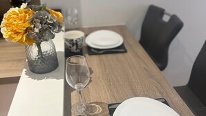 A dining table set with white plates, a glass, a patterned cup, and a vase with yellow flowers. - City Retreat Birmingham - Modern 2 Bed Apartment (Birmingham)
