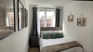 A bedroom with a bed, a dresser, a window with curtains, and framed pictures on the wall. - City Retreat Birmingham - Modern 2 Bed Apartment (Birmingham)
