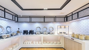 A modern kitchen with white tiled walls, wooden herringbone flooring, and various kitchen appliances and utensils on display. - yishangchongzuohotel (Chongzuo)