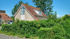 A two-story house with a pitched roof, a visible attic window, and a satellite dish. - Bungalow in Breskens Near Beach & Lighthouse (Breskens)