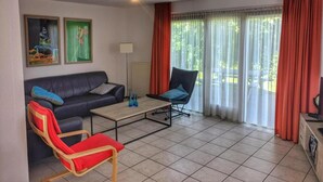 A living room with a sofa, a chair, a coffee table, and a television. - Bungalow in Breskens Near Beach & Lighthouse (Breskens)