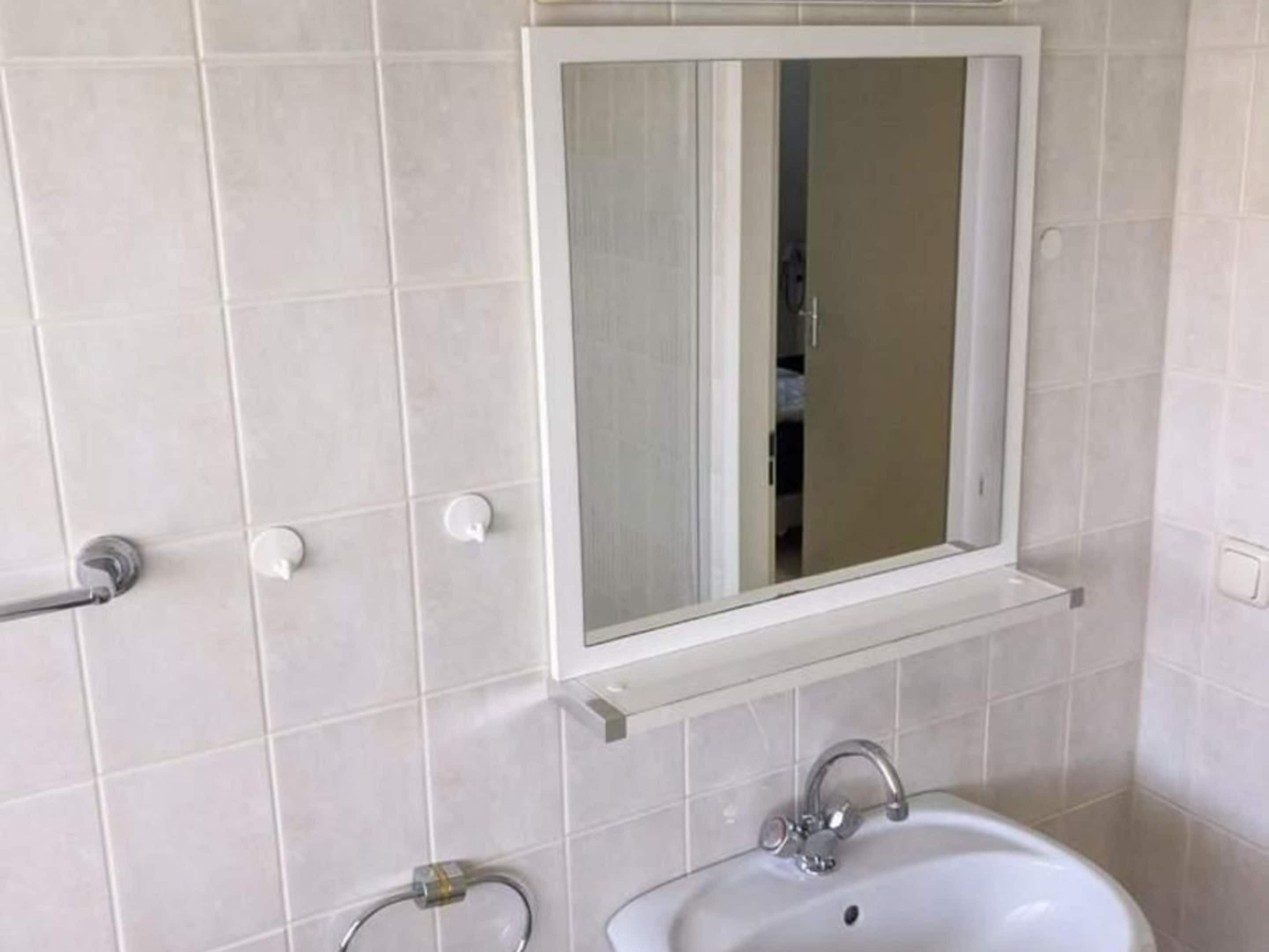 A bathroom with a white sink, a mirror, and a towel rack.