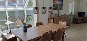 Un comedor con una mesa y sillas de madera, un jarrón con flores e iluminación colgante.