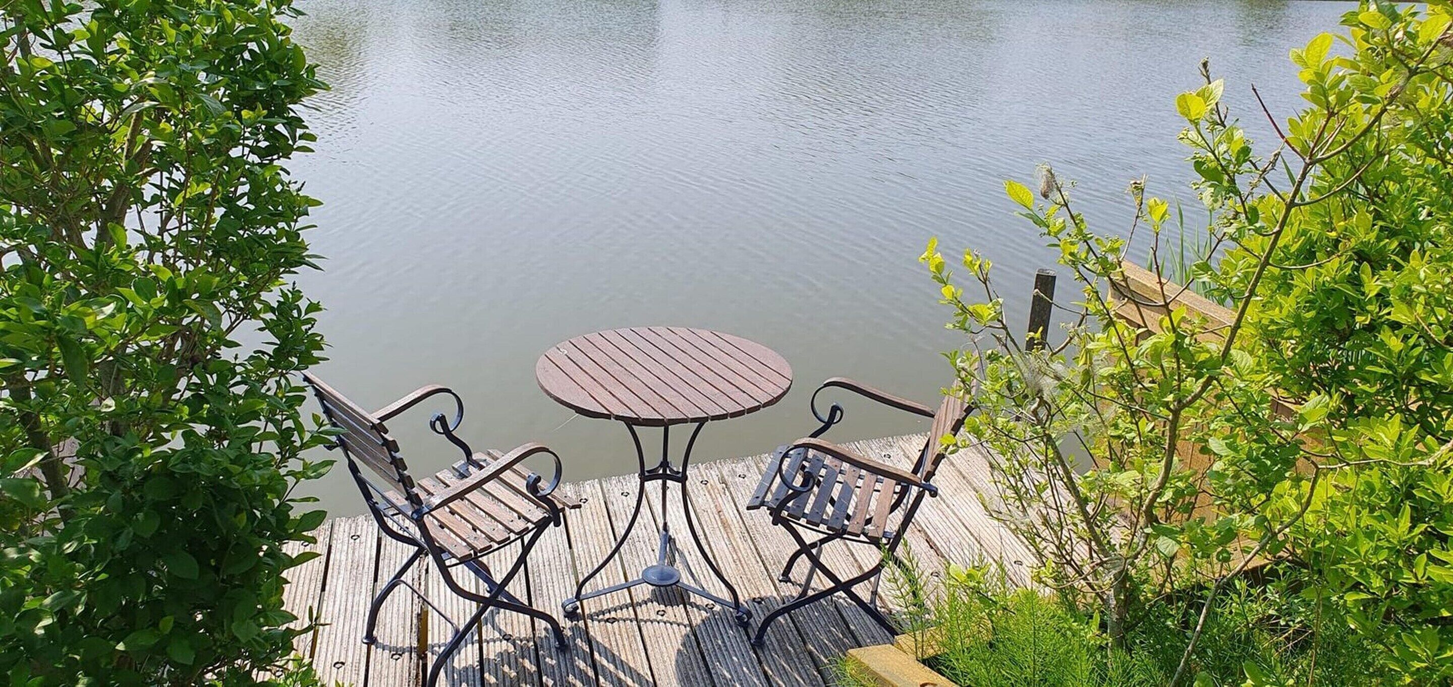 A wooden dock with a round table and four chairs.
