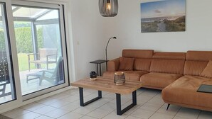 A living room with a sofa, a coffee table, a lamp, and a painting on the wall. - Eco-friendly Holiday Home (Breskens)
