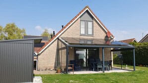 A house with a glass conservatory, a brick exterior, and a visible garage. - Eco-friendly Holiday Home (Breskens)