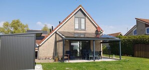 A house with a glass conservatory, a brick exterior, and a visible garage. - Eco-friendly Holiday Home (Breskens)