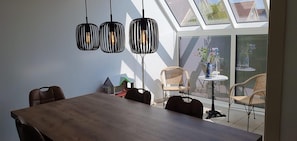 Un comedor con una mesa y sillas de madera, una pequeña casa decorativa, y una ventana con vista a un jardín.