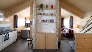 A cozy, well-lit attic room with a kitchen, dining area, and a seating area with a sofa and a fireplace. - Beautiful Chalet With hot tub (Stadl-Predlitz)