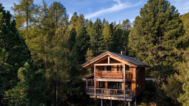 A wooden cabin with a balcony, surrounded by dense forest. - Beautiful Chalet With hot tub (Stadl-Predlitz)