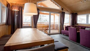 A wooden interior with a dining table, purple sofas, and a large window. - Beautiful Chalet With hot tub (Stadl-Predlitz)