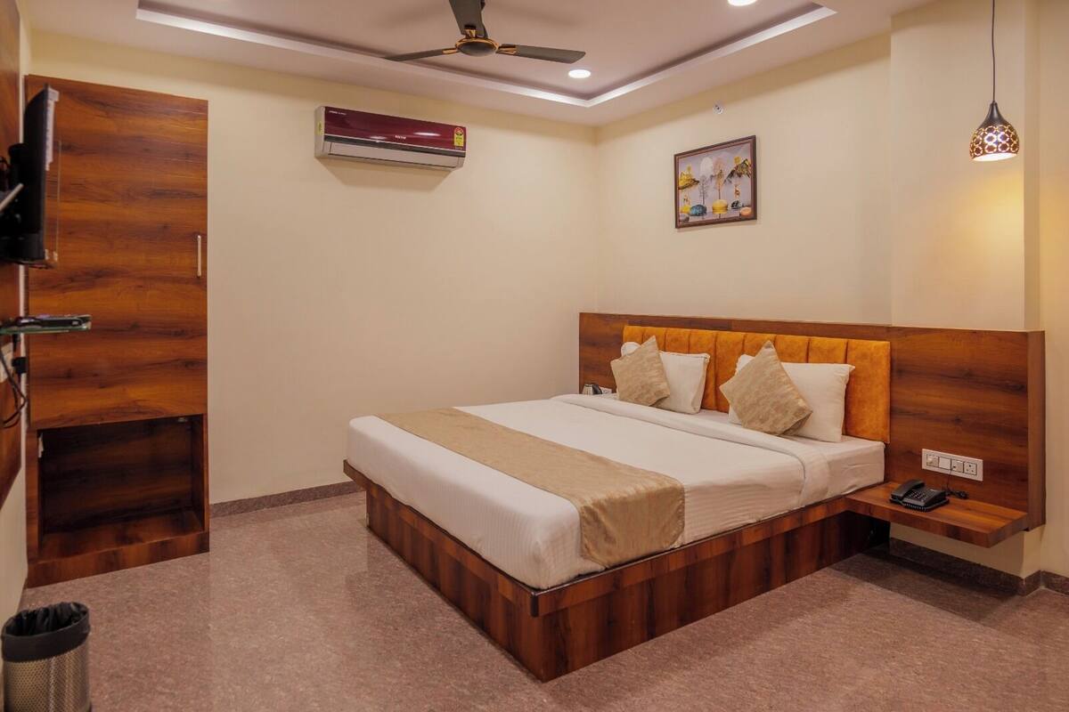 A bedroom with a wooden headboard, a bed with white linens, a bedside table with a lamp, and a ceiling fan.