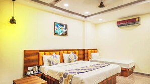 A hotel room with a wooden bed, bedside tables, a ceiling fan, an air conditioner, and a framed picture on the wall. - Hotel Dream Inn (Sanwer)